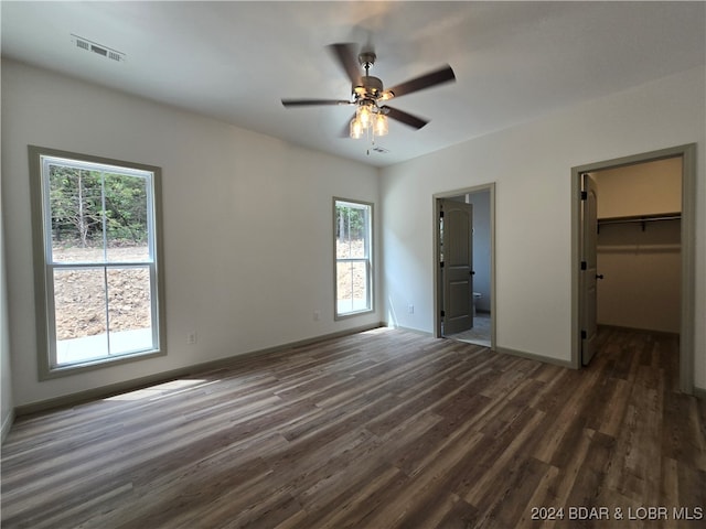 unfurnished bedroom with dark hardwood / wood-style flooring, a walk in closet, ceiling fan, and a closet