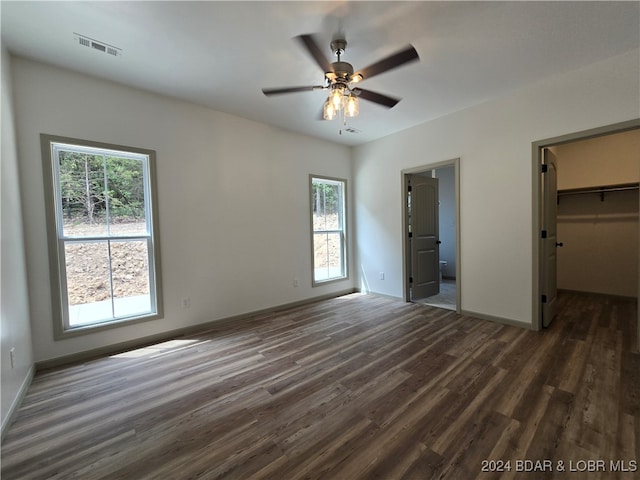 unfurnished bedroom with ceiling fan, a walk in closet, and multiple windows