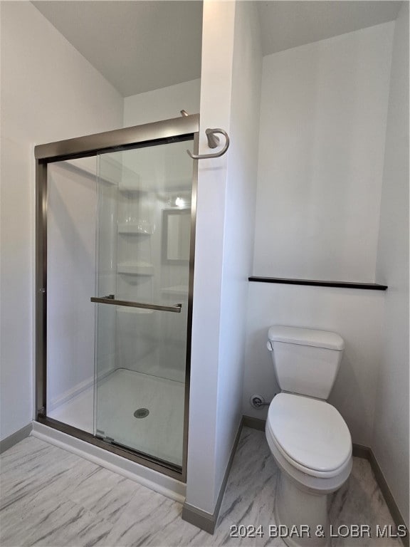 bathroom featuring toilet and a shower with door