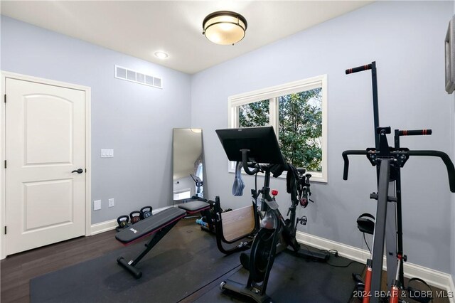 workout area with visible vents, baseboards, and dark wood-style floors
