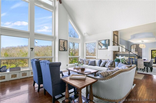 living area featuring high vaulted ceiling, dark wood finished floors, and stairs