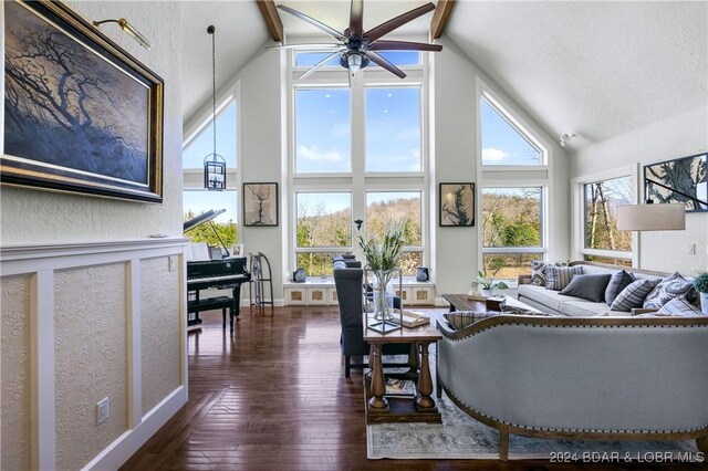 living area featuring a wealth of natural light, dark wood-style floors, a ceiling fan, and a textured wall