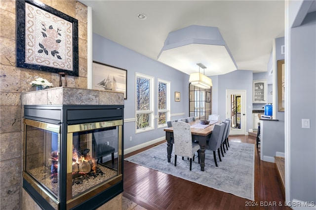 dining space featuring a fireplace and dark wood-type flooring