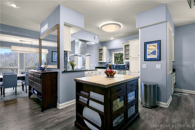 kitchen featuring dark wood-type flooring, kitchen peninsula, white cabinetry, and extractor fan