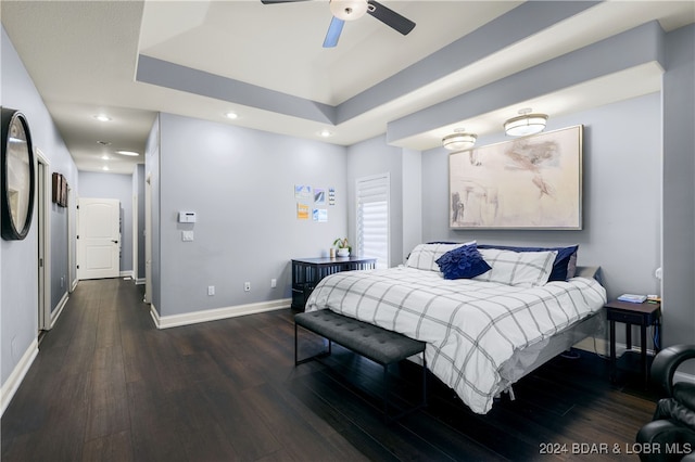 bedroom with a tray ceiling, dark wood-type flooring, and ceiling fan