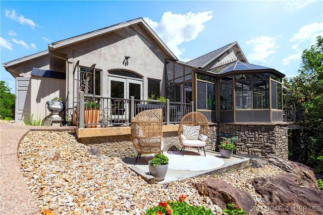 back of house with a patio area, a sunroom, and stucco siding