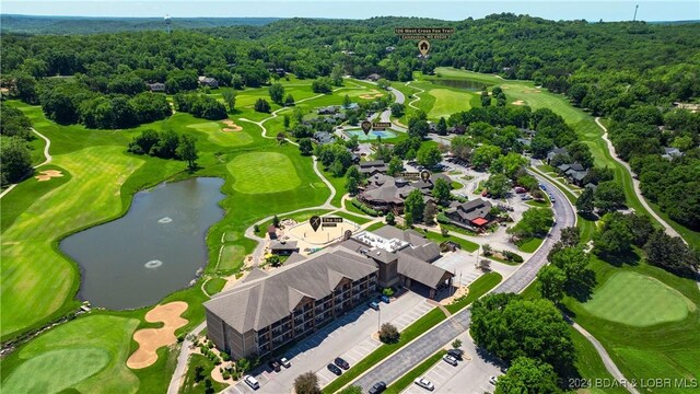 birds eye view of property featuring view of golf course, a water view, and a wooded view