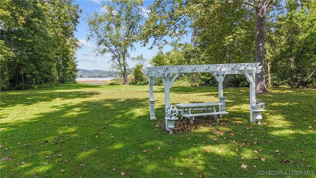 view of property's community featuring a yard and a pergola