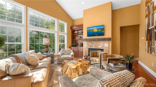 living room with a fireplace, hardwood / wood-style flooring, high vaulted ceiling, and built in features