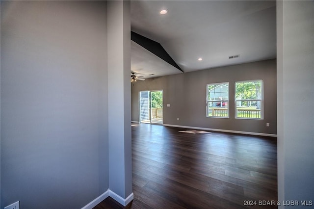 empty room featuring ceiling fan, dark hardwood / wood-style floors, and vaulted ceiling