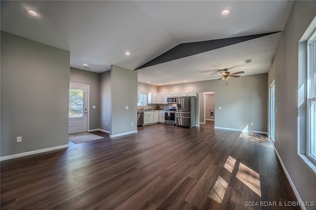 unfurnished living room with dark hardwood / wood-style floors, ceiling fan, sink, and vaulted ceiling