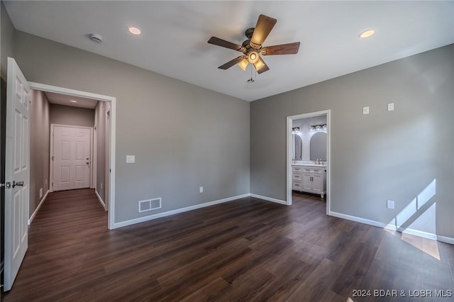 unfurnished bedroom featuring ensuite bathroom, ceiling fan, and dark wood-type flooring