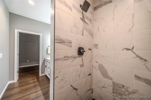 bathroom featuring a tile shower, vanity, and wood-type flooring