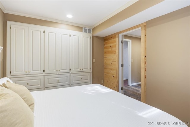 bedroom featuring ornamental molding, wooden walls, and hardwood / wood-style floors