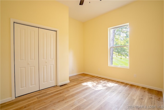 unfurnished bedroom with light hardwood / wood-style floors, ceiling fan, and a closet