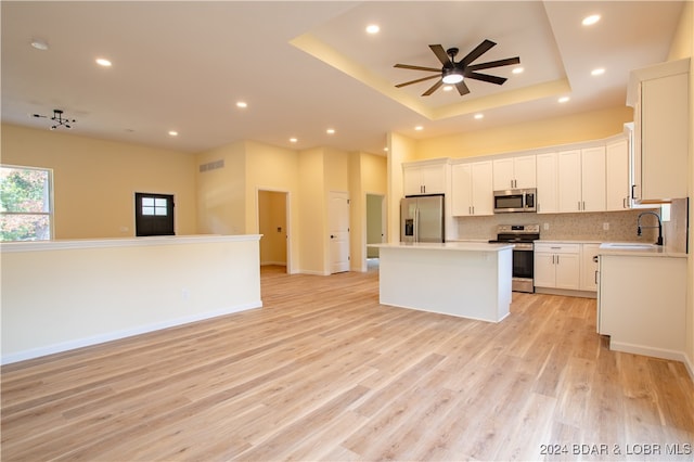 kitchen featuring ceiling fan, sink, a kitchen island, appliances with stainless steel finishes, and light hardwood / wood-style floors