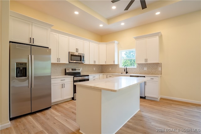 kitchen featuring a center island, white cabinets, light hardwood / wood-style flooring, stainless steel appliances, and ceiling fan