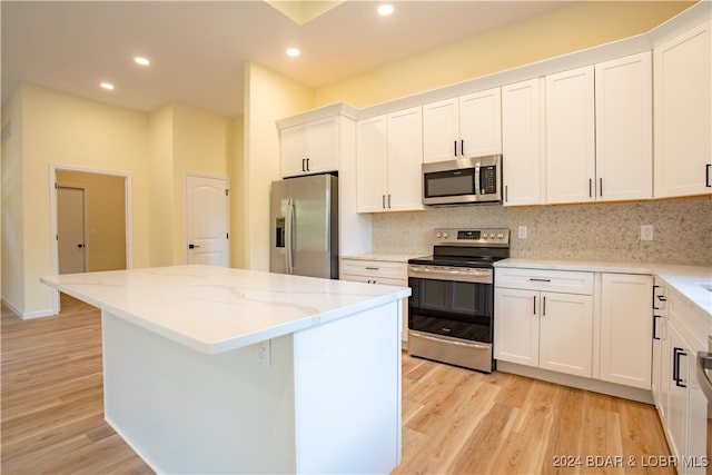 kitchen with appliances with stainless steel finishes, a kitchen island, light hardwood / wood-style flooring, and white cabinetry