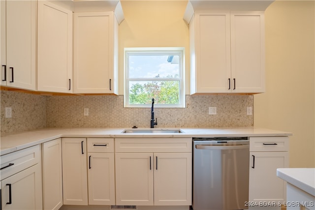 kitchen featuring stainless steel dishwasher, sink, tasteful backsplash, and white cabinets