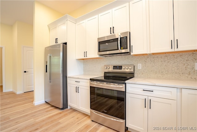 kitchen with appliances with stainless steel finishes, decorative backsplash, light hardwood / wood-style floors, and white cabinets