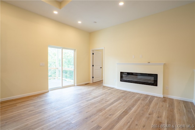 unfurnished living room featuring light hardwood / wood-style flooring and a towering ceiling