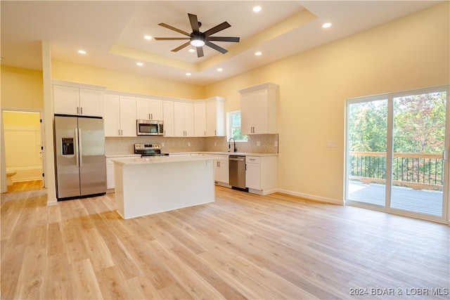 kitchen with appliances with stainless steel finishes, a raised ceiling, and white cabinetry