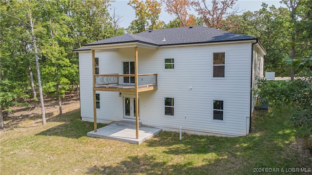 back of house featuring a balcony, a patio area, and a lawn