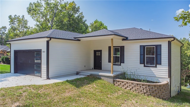 view of front facade featuring a porch, a garage, and a front yard