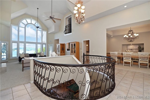 stairway featuring ceiling fan with notable chandelier, tile patterned floors, and high vaulted ceiling