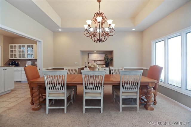 dining area with light tile patterned flooring, a raised ceiling, and a chandelier