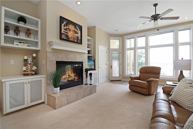 carpeted living room with ceiling fan and a fireplace