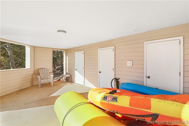 bedroom with light colored carpet, wooden walls, and two closets