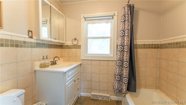 full bathroom with ornamental molding, tile walls, vanity, and toilet