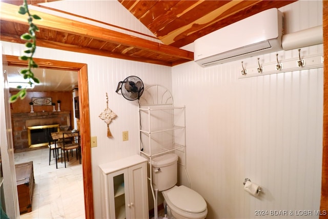 bathroom featuring an AC wall unit, wood walls, a fireplace, and toilet