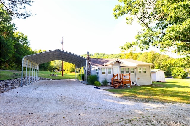 view of front of property featuring a front lawn, a shed, and a carport