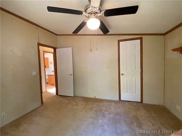 unfurnished bedroom with light carpet, ornamental molding, a textured ceiling, and ceiling fan