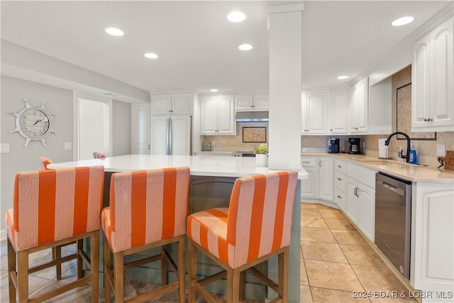 kitchen with a center island, sink, white cabinetry, a kitchen breakfast bar, and stainless steel dishwasher