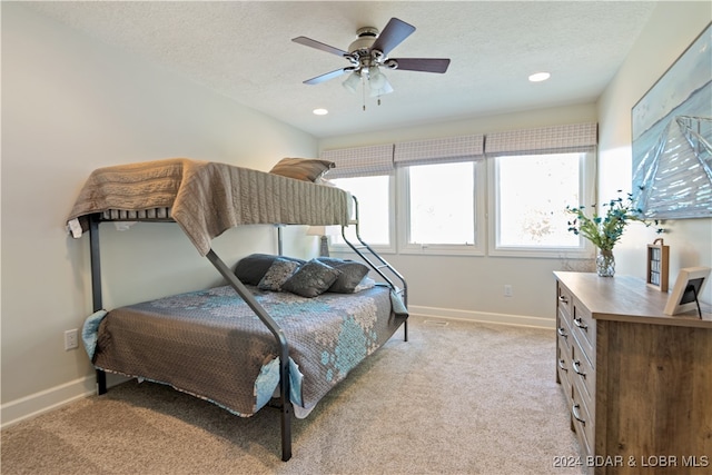 carpeted bedroom featuring ceiling fan and a textured ceiling