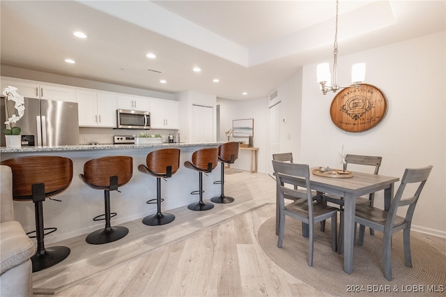 dining space with light hardwood / wood-style flooring and a notable chandelier