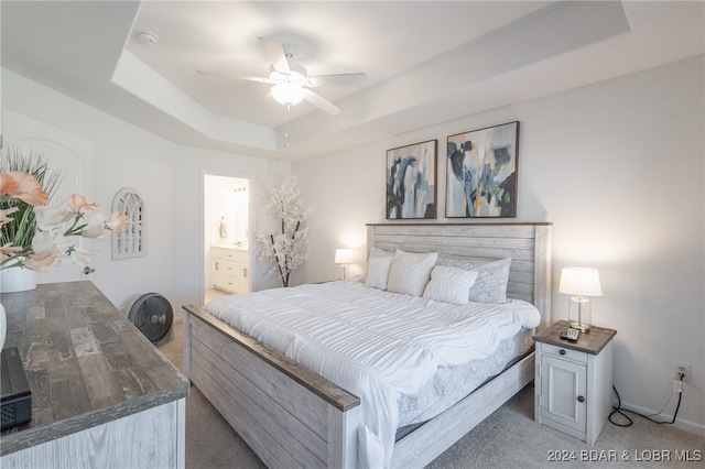 bedroom featuring carpet flooring, a tray ceiling, ceiling fan, and ensuite bathroom