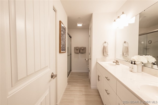 bathroom featuring hardwood / wood-style floors, vanity, a shower with shower door, and toilet