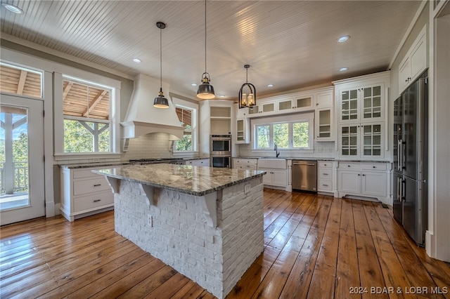 kitchen featuring white cabinets, hardwood / wood-style flooring, appliances with stainless steel finishes, and a kitchen island