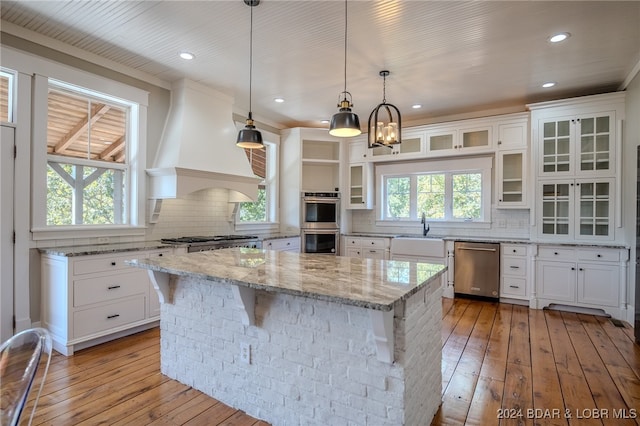 kitchen with stainless steel appliances, light wood-type flooring, custom range hood, and a center island