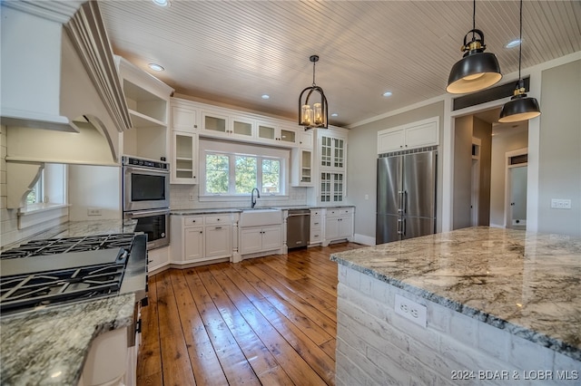 kitchen featuring pendant lighting, appliances with stainless steel finishes, white cabinets, and light stone countertops