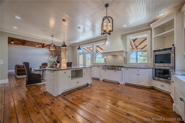 kitchen with light hardwood / wood-style flooring, hanging light fixtures, custom range hood, and stainless steel appliances