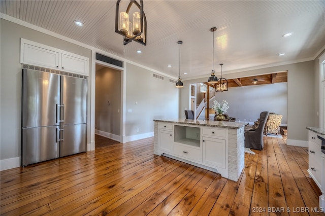 kitchen with stainless steel built in fridge, pendant lighting, light stone countertops, and white cabinetry