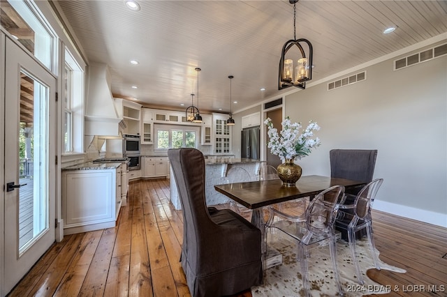 dining space featuring hardwood / wood-style flooring, wood ceiling, and a notable chandelier