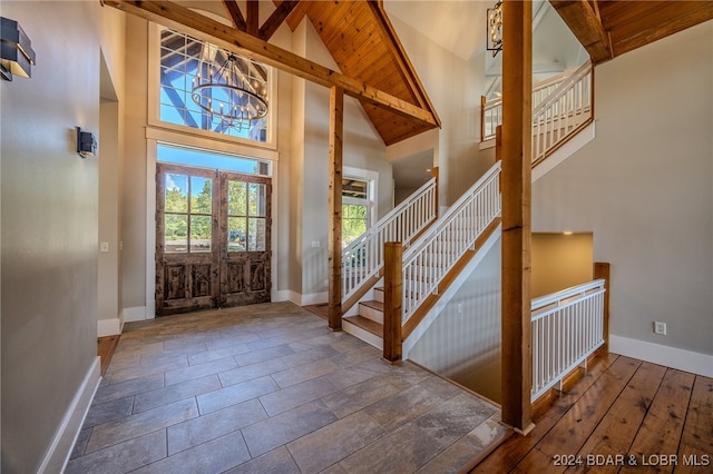 entrance foyer featuring wood ceiling, high vaulted ceiling, beamed ceiling, french doors, and a chandelier