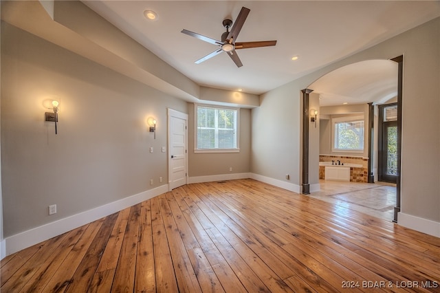 empty room featuring light wood-type flooring, ceiling fan, and a healthy amount of sunlight