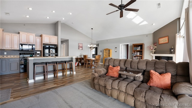 living room with ceiling fan with notable chandelier, sink, high vaulted ceiling, and dark hardwood / wood-style flooring